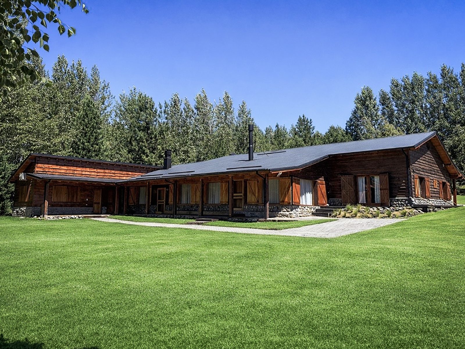 Patagonian hunting lodge with wooden architecture and green lawn